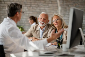 Oud koppel kijkt geschokt terwijl ze met een zorgspecialist over hun verzekering 2025