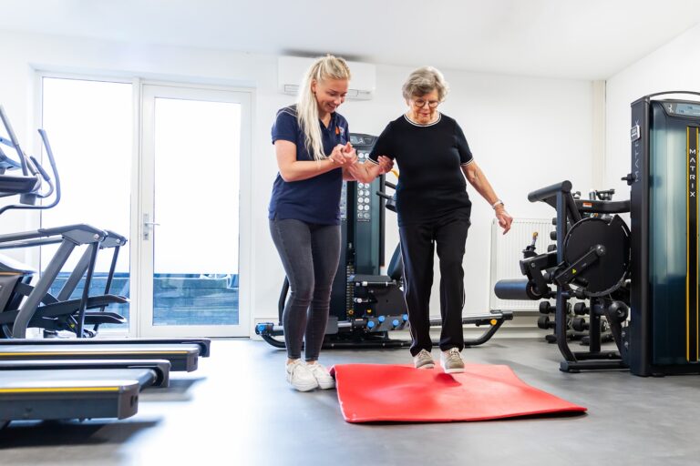 Mevrouw wordt aan de hand gepakt door andere vrouw in een sportzaal voor haar goede voornemens.