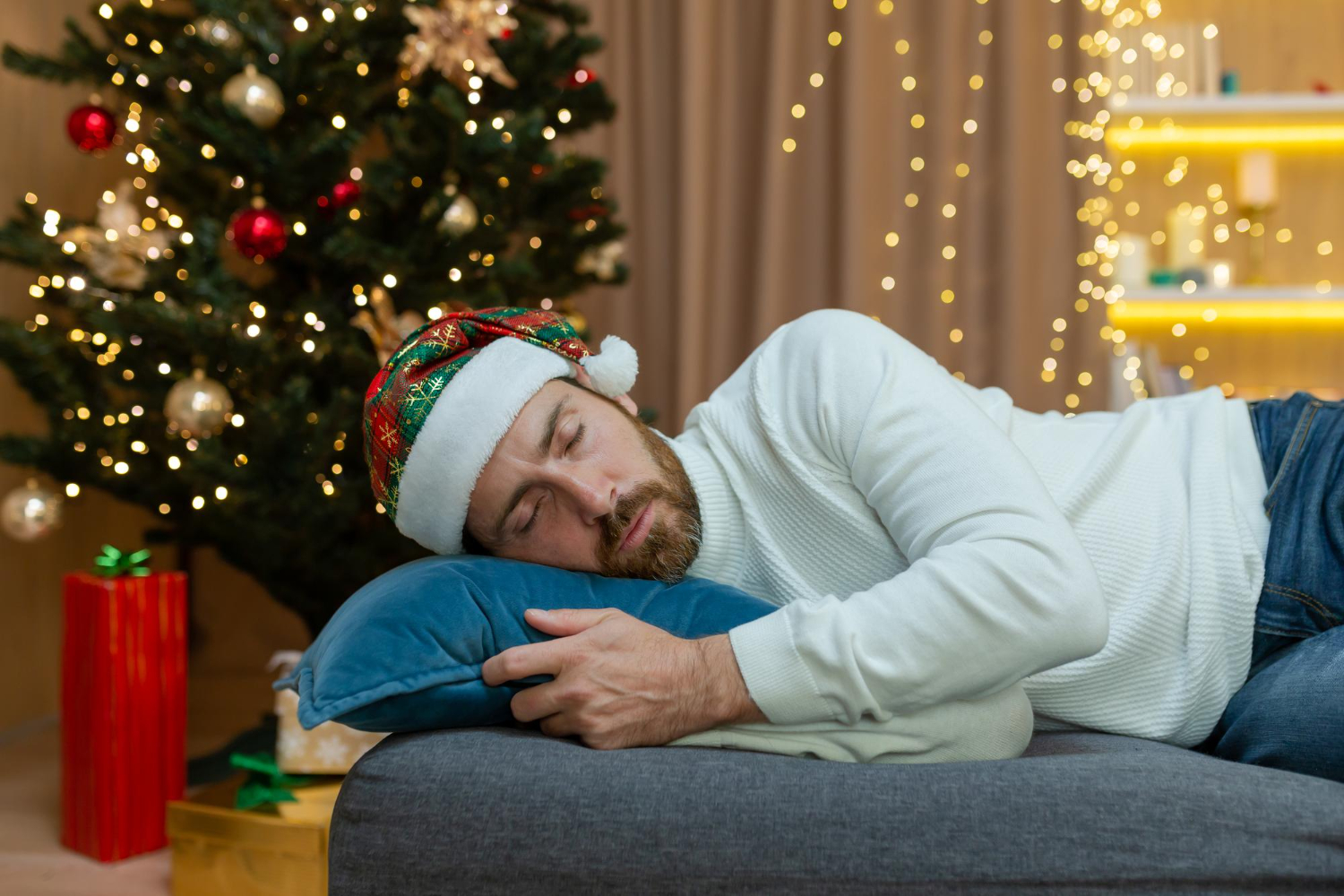 Man met kerstmuts op zijn hoofd ligt op de bank voor rust en herstel